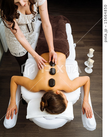 Massage therapist applying a hot stone massage 15664850