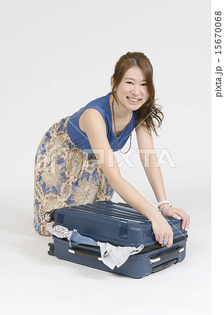 スーツケースに荷物を山のように詰め込む女性 スーツケースに荷物を山のように詰め込む女性 15670068