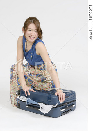 スーツケースに荷物を山のように詰め込む女性 15670075