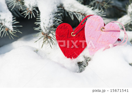 red hearts toy in snowfall on fir tree 15671541