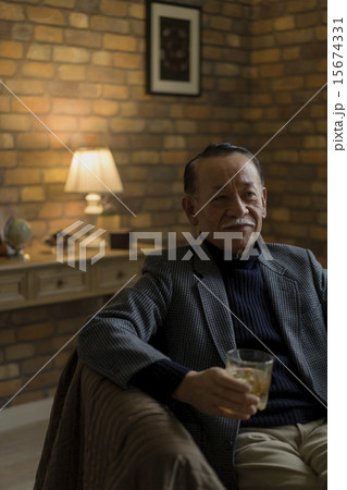 お酒の入ったグラスを持って座るシニア男性 15674331