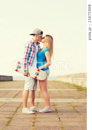 smiling couple with skateboard kissing outdoors smiling couple with skateboard kissing outdoors 15675908