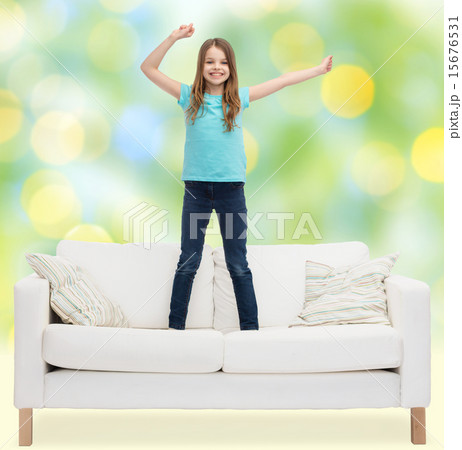 smiling little girl jumping on sofa 15676531
