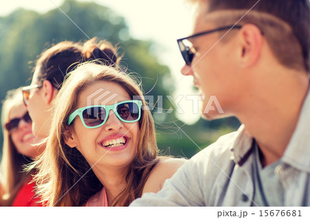 group of smiling friends sitting on city street 15676681
