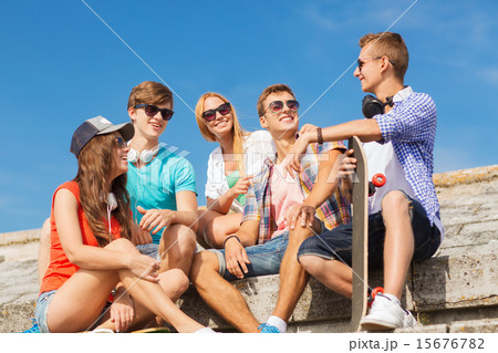 group of smiling friends sitting on city street group of smiling friends sitting on city street 15676782