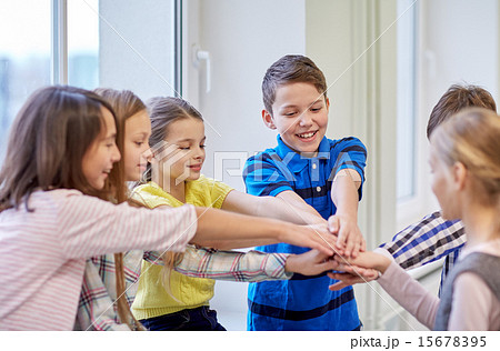 group of smiling school kids putting hands on top 15678395