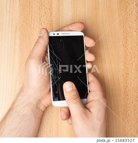 Hands holding a phone with a broken screen Hands holding a phone with a broken screen 15683527