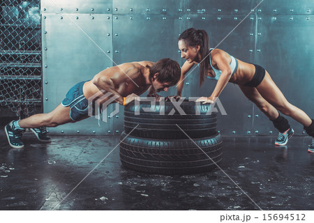 Sportswomen. Fit sporty woman and man doing push ups on tire strength power training concept Sportswomen. Fit sporty woman and man doing push ups on tire strength power training concept 15694512