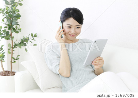 タブレットを見ながら電話する笑顔の女性 　 15697008