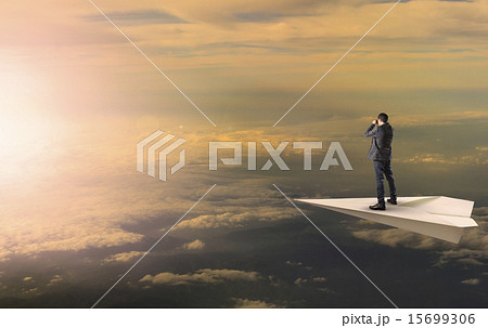 business man standing and spying binocular on papet plane agains 15699306