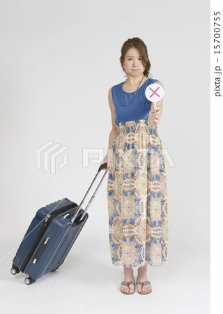 キャリーバッグの傍でバツのプレートを出す女性 15700755