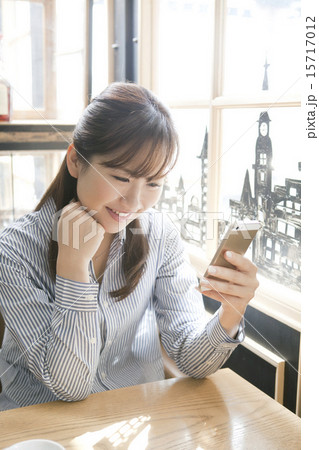 カフェで携帯電をを見る若い女性 15717012