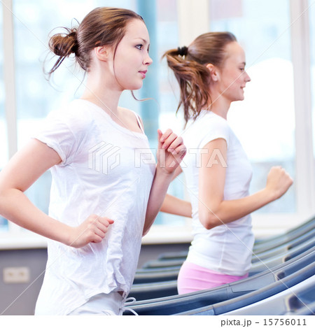 Two young sporty women run on machine 15756011
