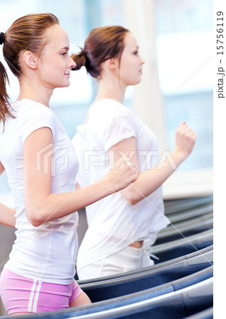 Two young sporty women run on machine Two young sporty women run on machine 15756119