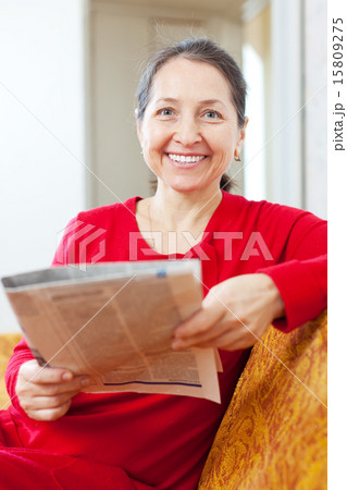 cheerful positive mature woman reads newspaper 15809275