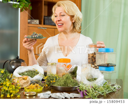 Mature woman with herbs at table 15809453