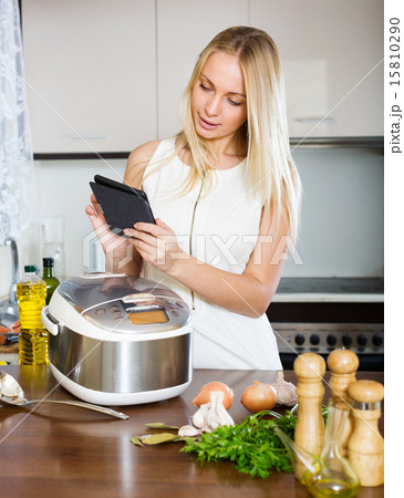 housewife reading ereader and cooking with multicooker housewife reading ereader and cooking with multicooker 15810290