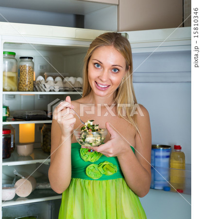Girl eating salad from fridge Girl eating salad from fridge 15810346
