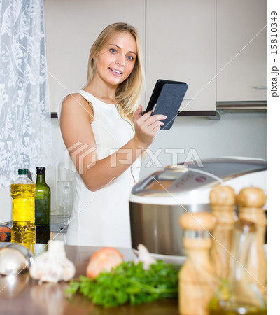 Woman reading ereader near multicooker 15810349