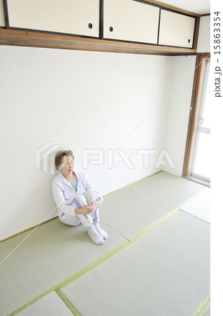 何もない部屋で一人で三角座りをしている孤独な高齢者女性 15863354