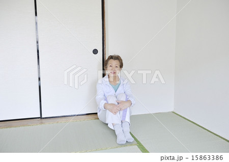 何もない部屋で一人で三角座りをしている孤独な高齢者女性 15863386
