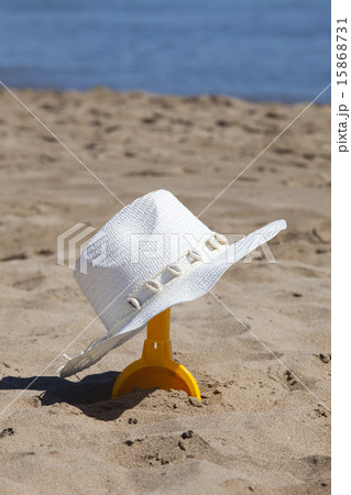 Straw hat hangs onto an beach shovel Straw hat hangs onto an beach shovel 15868731