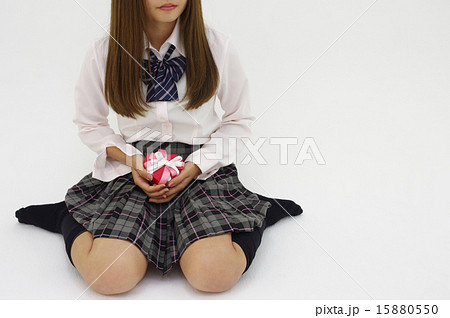 女の子座りでプレゼントを持つ女性 主体左口あり右向きの写真素材
