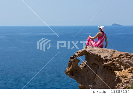 Woman in a long dress  sitting on a rock on the sea 15887154