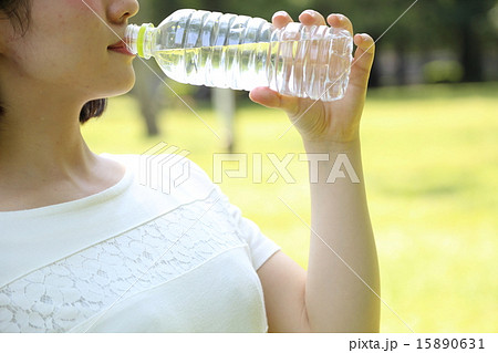ペットボトルの水を飲む女性の口元の写真素材