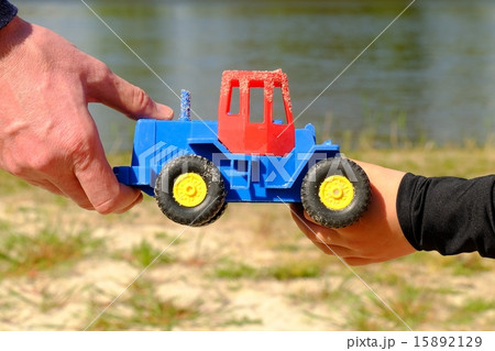 Father's large hand pass plastic toy truck to hand Father's large hand pass plastic toy truck to hand 15892129
