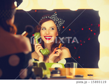 woman with dial phone applying cosmetics woman with dial phone applying cosmetics 15893119