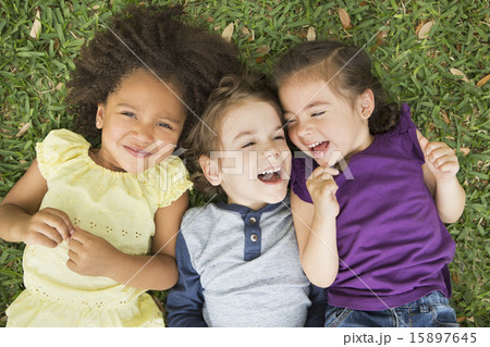 Three children lying on their backs on the grass, looking up and laughing. Three children lying on their backs on the grass, looking up and laughing. 15897645