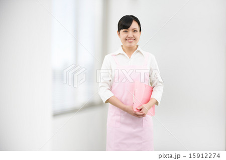 窓際に立つエプロンをした若い女性のイメージ 15912274