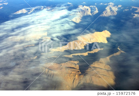 雲間から見える山の頂が朝日に照らし出された南米アンデス山脈 15972576