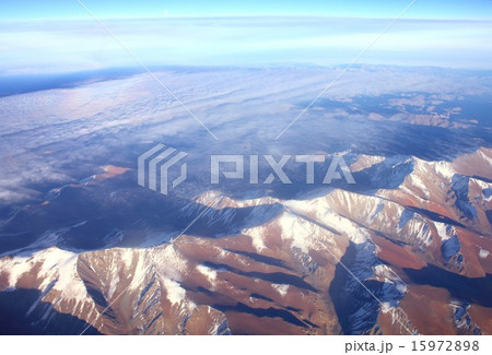 雲間に見える山々の頂が朝日に照らし出された南米アンデス山脈 15972898