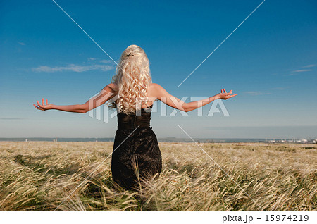 The girl in a black dress standing in the grain field arms sprea 15974219