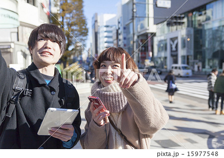 カップル スマホとタブレットを持ってお店探しイメージ 原宿ラフィーレ前の写真素材