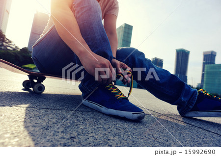 skateboarder tying shoelace at skate park skateboarder tying shoelace at skate park 15992690