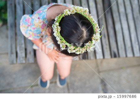 花の冠をかぶってベンチに座る女の子の写真素材