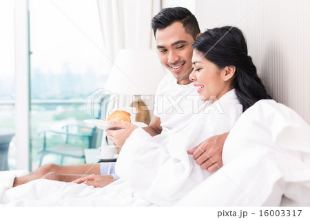 Asian couple lounging in bed at morning Asian couple lounging in bed at morning 16003317