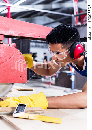 Carpenter in Asian workshop with circular saw 16003333