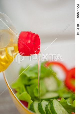 Someone is making healthy tasty salad filling it up 16007728