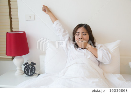 Sleepy asian woman yawning in bed at home 16036863