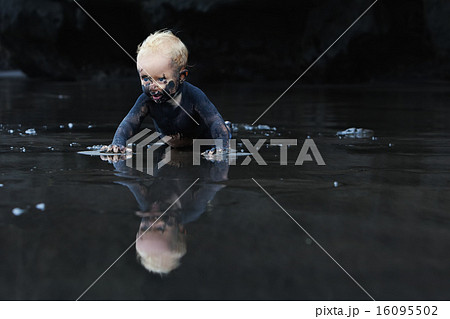 Dirty child crawling on wet black sand beach 16095502