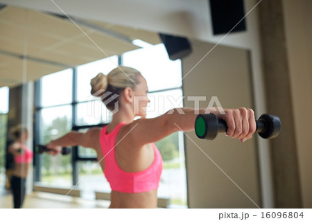 woman with dumbbells flexing muscles in gym 16096804