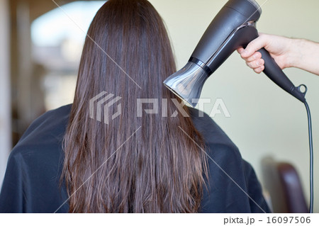 stylist hand with fan dries woman hair at salon 16097506