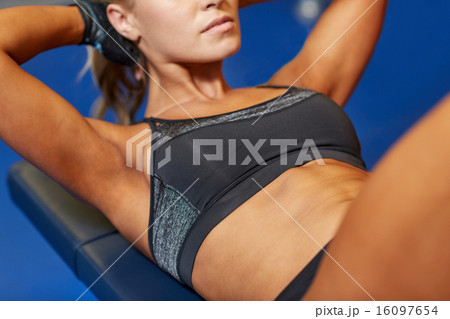 woman flexing abdominal muscles on bench in gym woman flexing abdominal muscles on bench in gym 16097654