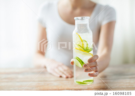 close up of woman with fruit water in glass bottle 16098105