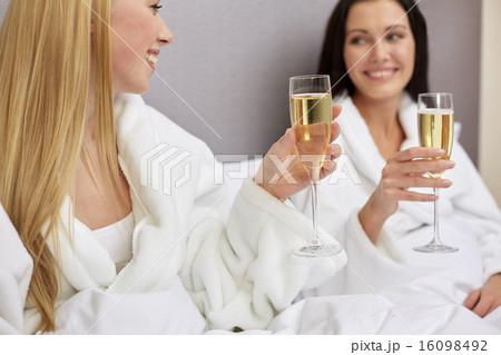 happy women in bathrobes with champagne glasses happy women in bathrobes with champagne glasses 16098492