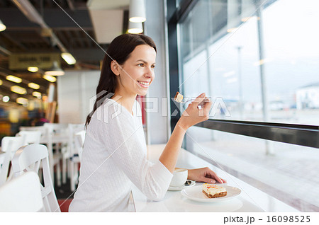 smiling young woman with cake and coffee at cafe 16098525